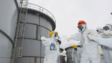 Fukušimos gubernatorius Juhei Sato (su oranžiniu šalmu) apžiūri konteinerius su radioaktyviu vandeniu