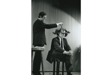 Willem de Ridder dengia Emmetto Williamso galvą kopūsto lapais Robert‘o Filliou performanse 13 Façons d’employer le crâne d’Emmett Williams, Kleine Komedie teatras, Amsterdamas, 1963 m. gruodžio 18 d. Nuotr. Dorine van der Klei