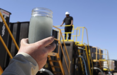 Stiklainyje prieš šviesą laikomas panaudotas hidraulinio skaldymo procese vanduo perdirbimo vietoje Midlende, Teksase, 2013 m. rugsėjo 24-ąją. | AP FOTO/PAT SULLIVAN