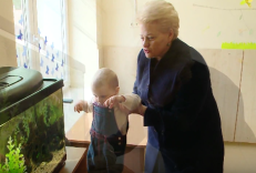 Prezidentė D. Grybauskaitė eilinės fotosesijos metu su vaiku rankose. 