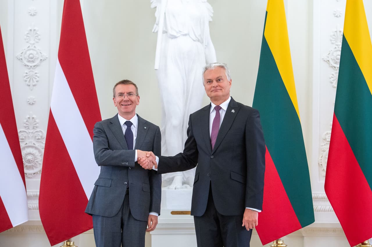 **Latvių homoseksualas Rinkevičius(kairėje) spaudžia ranką lietuvių heteroseksualui Nausėdai.**